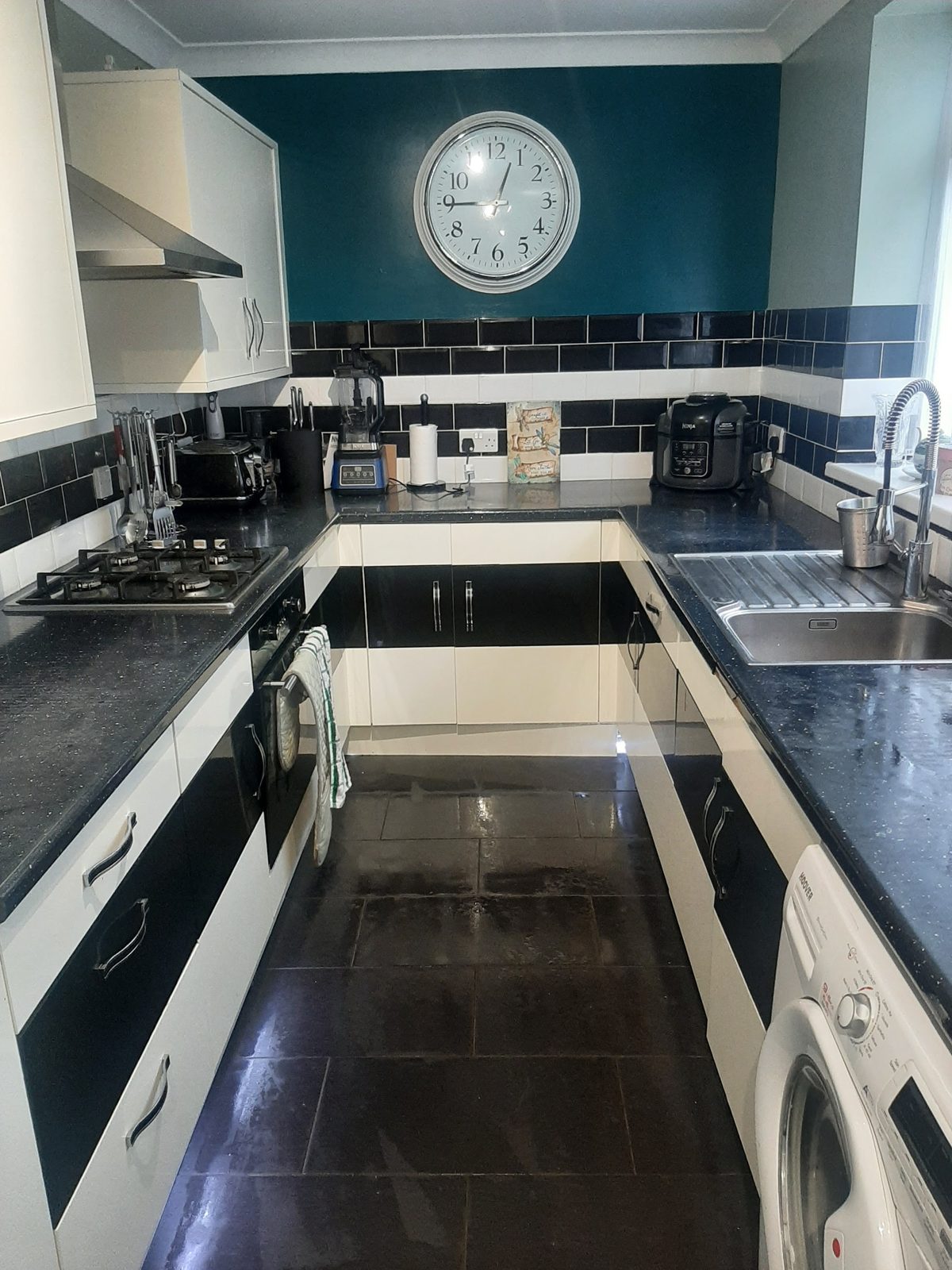 Kitchen with a deep teal painted wall above dark tiles